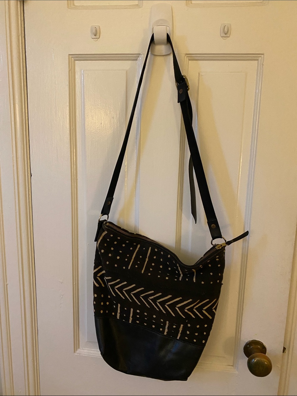 African mud cloth and black leather bottom, pocket and adjustable strap.